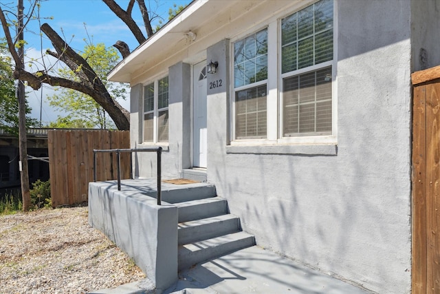 entrance to property with stucco siding and fence