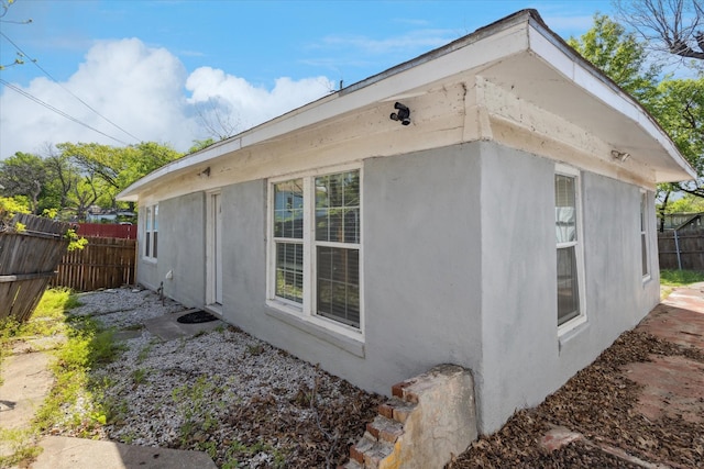 view of home's exterior with stucco siding and fence
