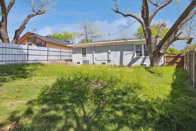 back of property with a fenced backyard, a lawn, and stucco siding