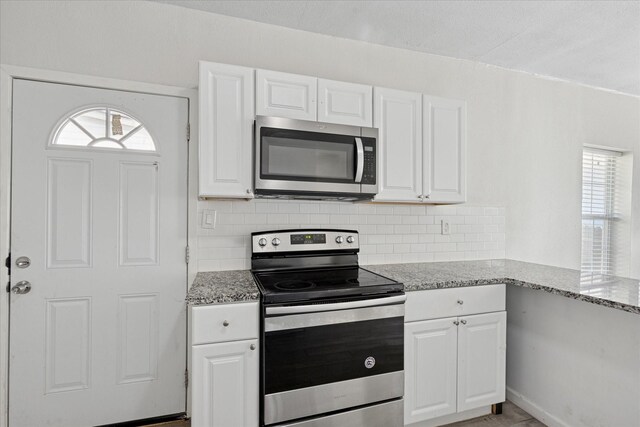 kitchen with appliances with stainless steel finishes, white cabinets, and a healthy amount of sunlight