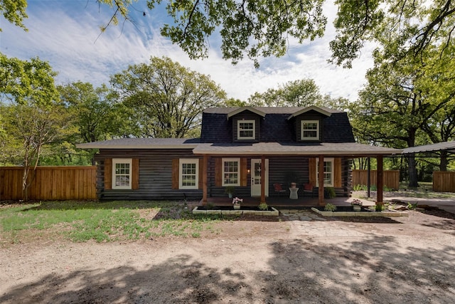 view of front of house with log siding, fence, a shingled roof, and covered porch