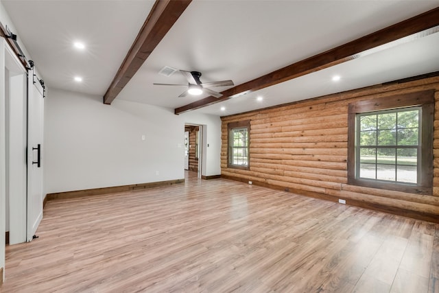 unfurnished room with log walls, a barn door, a wealth of natural light, recessed lighting, and light wood-style flooring