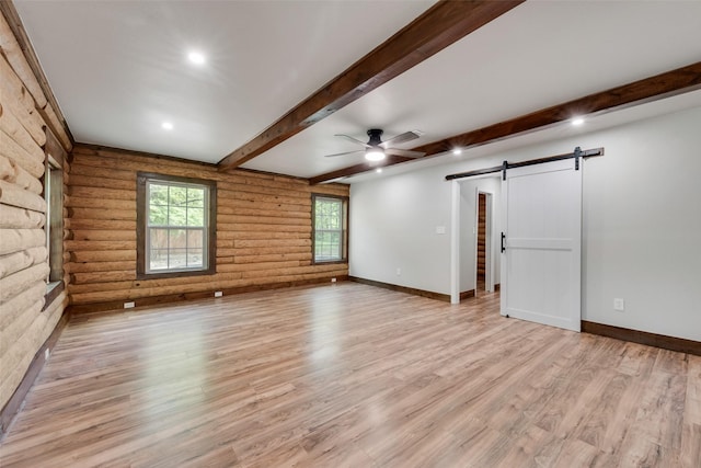 unfurnished living room featuring a ceiling fan, rustic walls, a barn door, and light wood finished floors