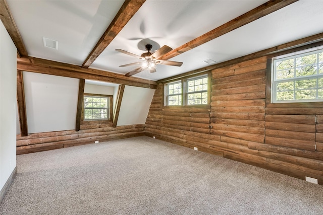 empty room featuring log walls, a wealth of natural light, and carpet floors