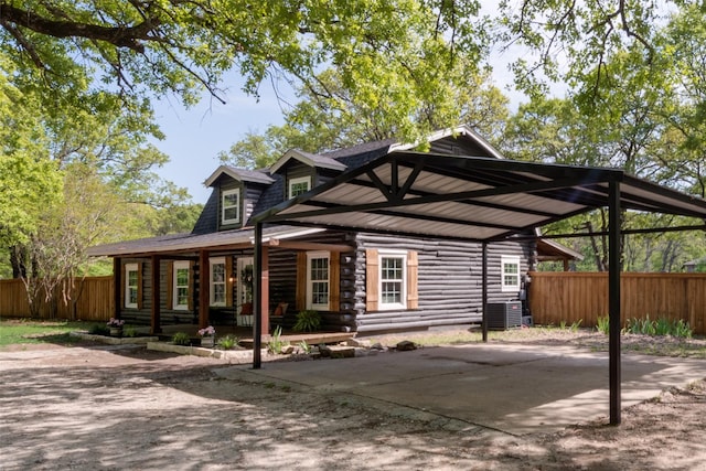 back of house featuring log exterior, a detached carport, and fence