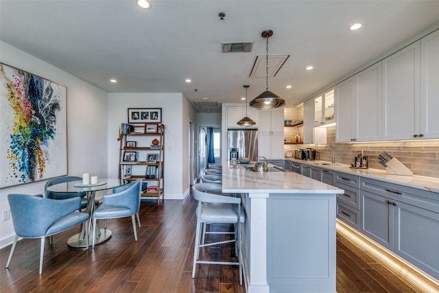 4611 Travis St Unit 1408B, Dallas, TX 75205 - kitchen featuring stainless steel fridge, dark wood-type flooring, a sink, a kitchen bar, and light stone counters