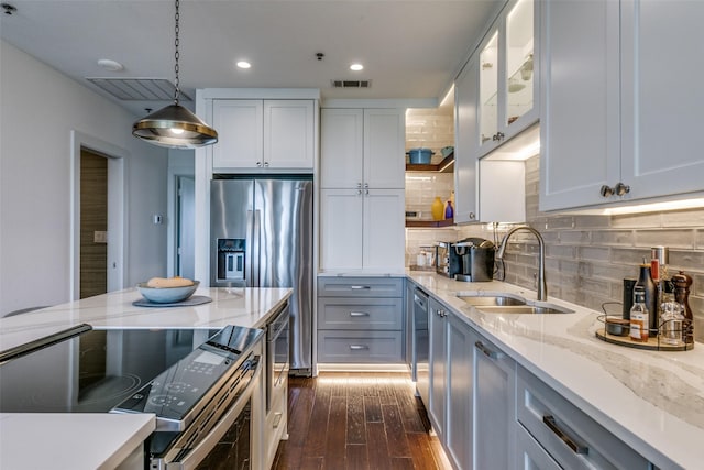 4611 Travis St Unit 1408B, Dallas, TX 75205 - kitchen featuring appliances with stainless steel finishes, a sink, dark wood-style floors, light stone counters, and decorative light fixtures