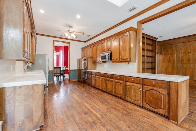 5 Cypress Ct, Heath, TX 75032 - kitchen with appliances with stainless steel finishes, ornamental molding, light wood-type flooring, ceiling fan, and tasteful backsplash