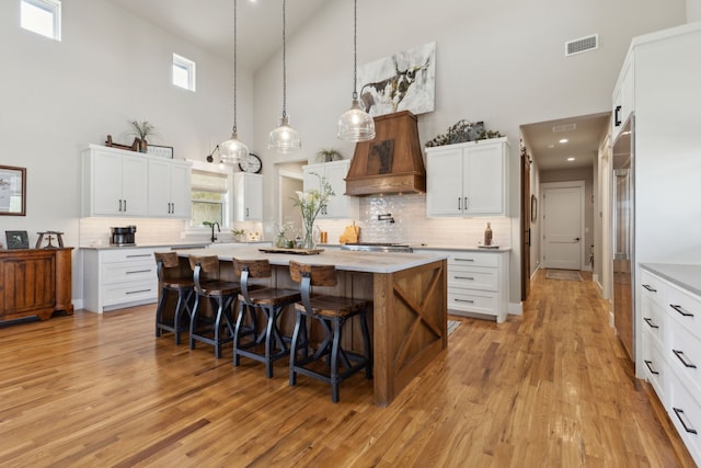 3241 Bridgegate Ave, Northlake, TX 76247 - kitchen featuring high vaulted ceiling, custom range hood, a kitchen bar, light countertops, and backsplash
