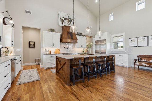 3241 Bridgegate Ave, Northlake, TX 76247 - kitchen with stainless steel appliances, high vaulted ceiling, premium range hood, light countertops, and a breakfast bar area