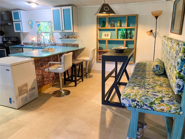 kitchen with exhaust hood, a sink, a kitchen breakfast bar, a peninsula, and range with gas stovetop