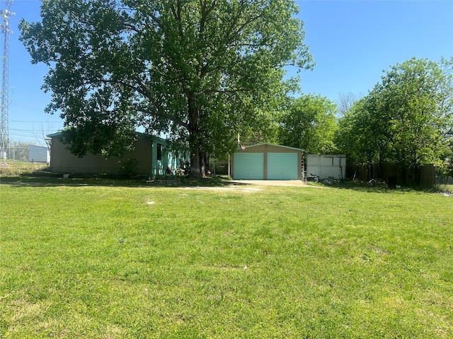 view of yard featuring fence, an outdoor structure, and a garage