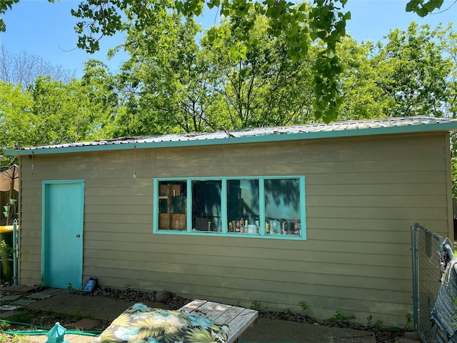 back of house with metal roof and fence