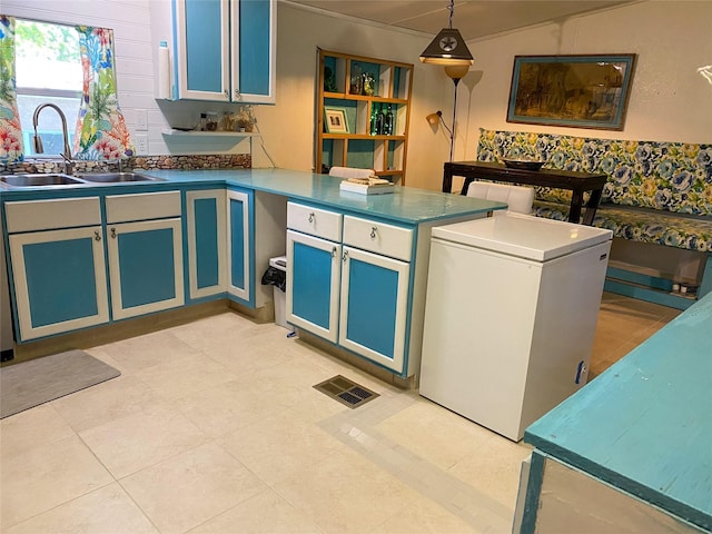 kitchen with white fridge, a peninsula, pendant lighting, and a sink
