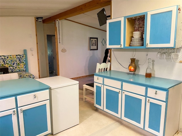 kitchen featuring beam ceiling, light countertops, and refrigerator