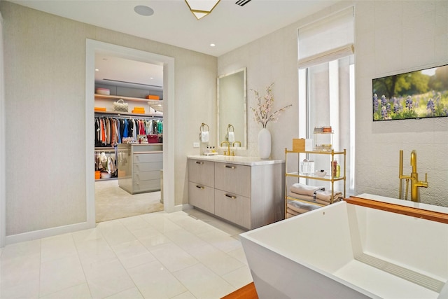 full bathroom featuring baseboards, a freestanding tub, vanity, and a spacious closet