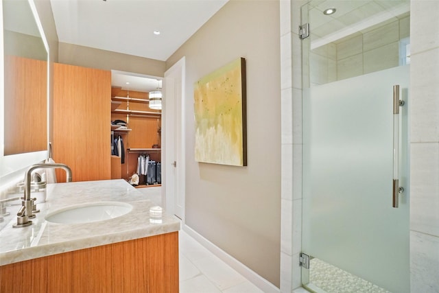 full bath featuring a shower stall, vanity, baseboards, a spacious closet, and tile patterned flooring
