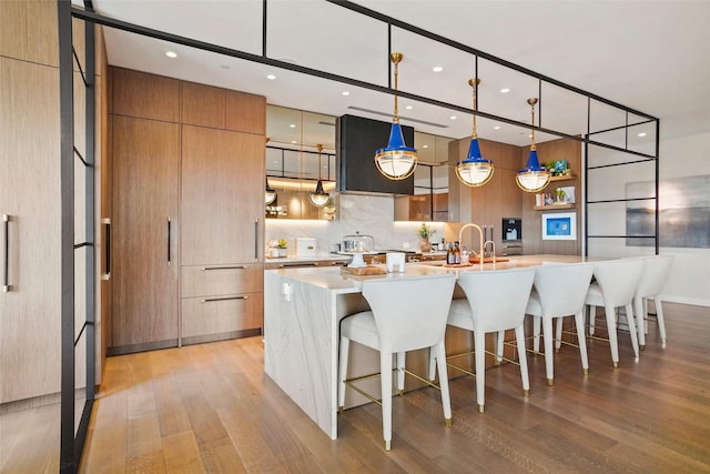 kitchen featuring a breakfast bar area, light wood-style floors, modern cabinets, and extractor fan