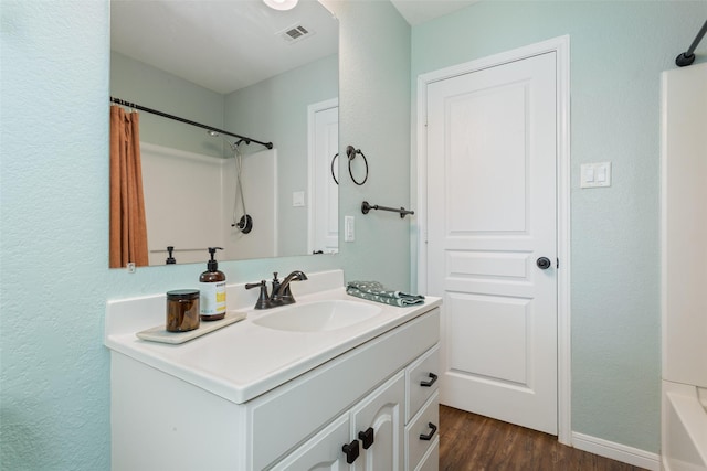 full bathroom with vanity, a textured wall, a shower with curtain, visible vents, and wood finished floors