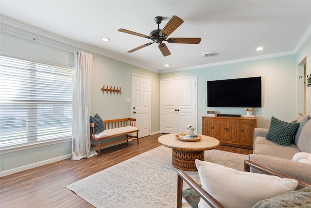 living room featuring ceiling fan, ornamental molding, visible vents, wood finished floors, and baseboards