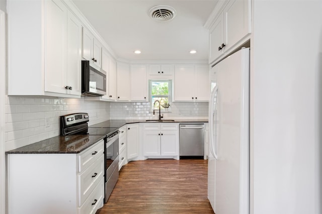 kitchen with white cabinetry, visible vents, appliances with stainless steel finishes, wood finished floors, and a sink