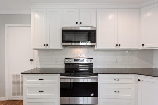 kitchen with tasteful backsplash, ornamental molding, visible vents, and stainless steel appliances