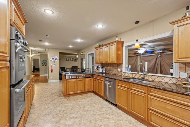 kitchen featuring a sink, decorative backsplash, a peninsula, appliances with stainless steel finishes, and recessed lighting