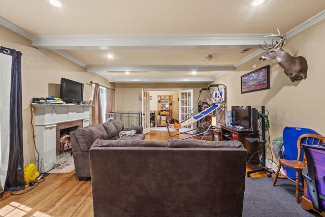 living area featuring crown molding, beam ceiling, wood finished floors, and a fireplace