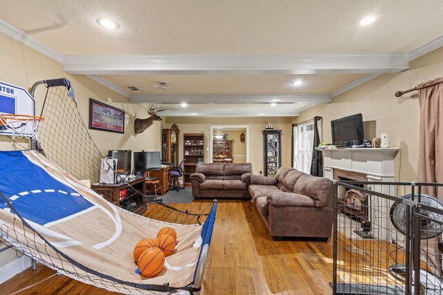 living area featuring crown molding, hardwood / wood-style floors, a fireplace, beam ceiling, and visible vents