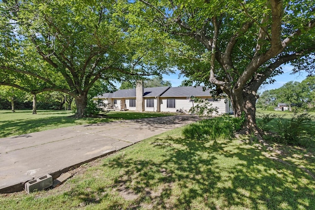 ranch-style home featuring concrete driveway, a front lawn, a chimney, and a garage