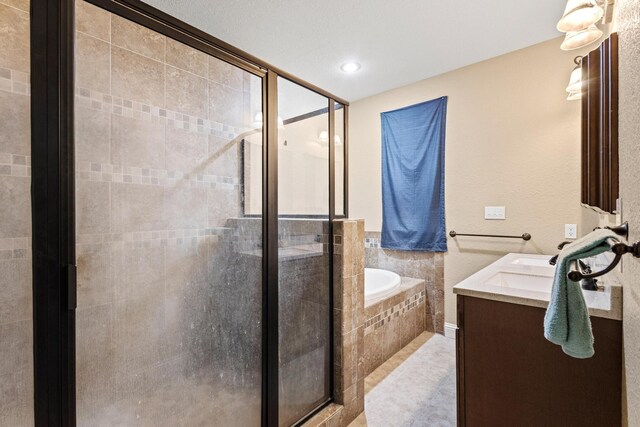 bathroom featuring a shower stall, a garden tub, tile patterned floors, and vanity