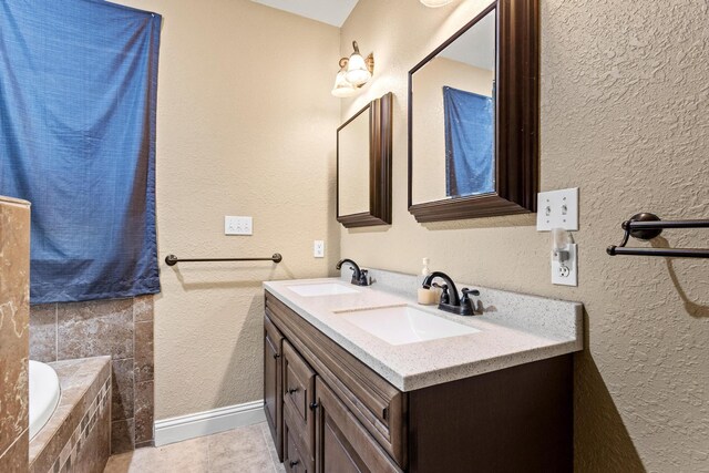 bathroom featuring a textured wall, a sink, and double vanity