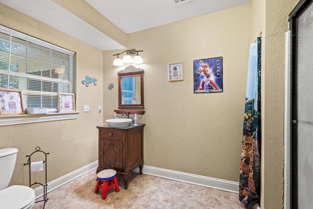 full bathroom with vanity, a shower with shower door, baseboards, toilet, and visible vents
