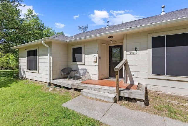property entrance featuring a lawn and a shingled roof