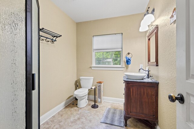 bathroom with toilet, vanity, and baseboards