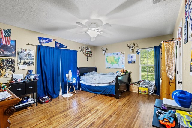 bedroom featuring wood finished floors, a textured ceiling, and ceiling fan