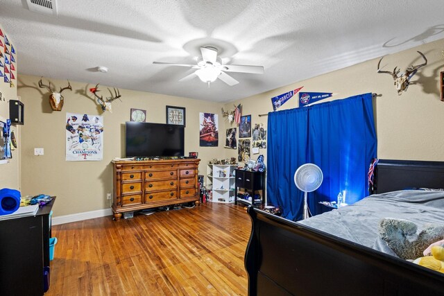 bedroom featuring a textured ceiling, wood finished floors, visible vents, and a ceiling fan