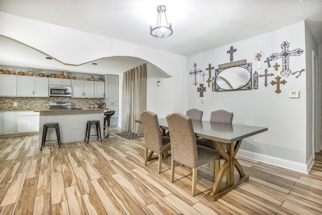 dining space with light wood-style flooring and baseboards