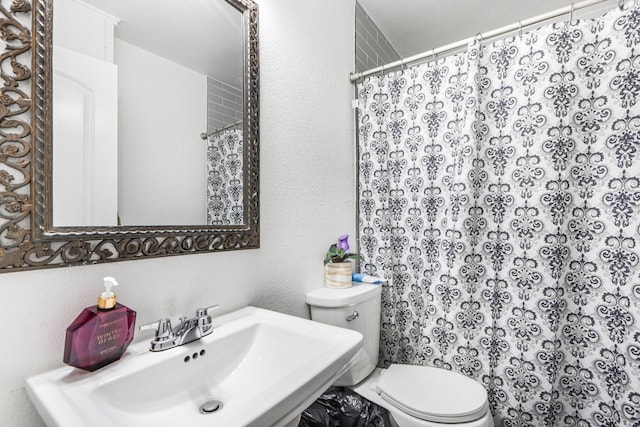 full bathroom featuring a shower with shower curtain, a sink, and toilet