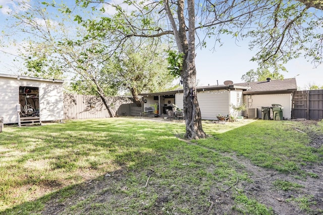 view of yard with a fenced backyard, central AC, and an outbuilding