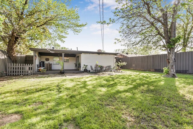 rear view of property featuring a fenced backyard, a patio, and a lawn