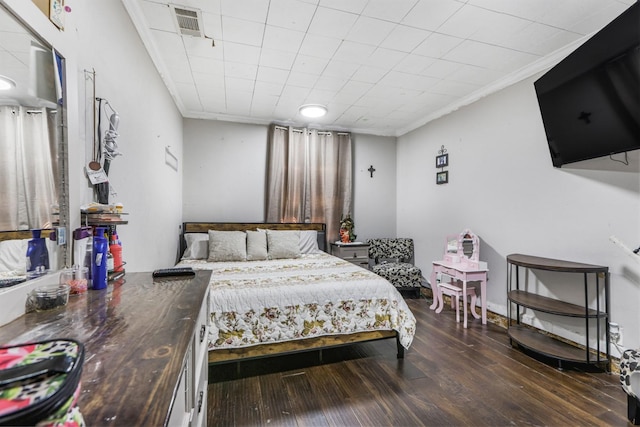 bedroom with hardwood / wood-style floors, ornamental molding, and visible vents