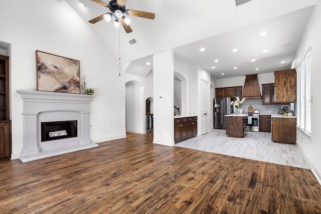 1208 Claire St, Lantana, TX 76226 - unfurnished living room featuring light wood-style floors, arched walkways, ceiling fan, recessed lighting, and high vaulted ceiling