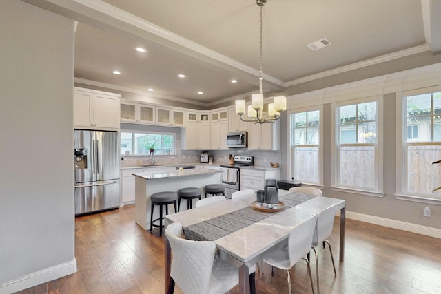 dining space with crown molding, plenty of natural light, a chandelier, baseboards, and recessed lighting