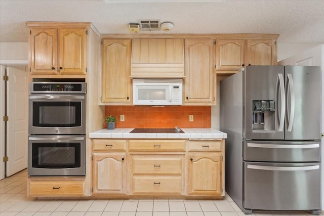 10010 Lost Oak Ridge Dr, Woodway, TX 76712 - kitchen with stainless steel appliances, a textured ceiling, light brown cabinets, and tile counters