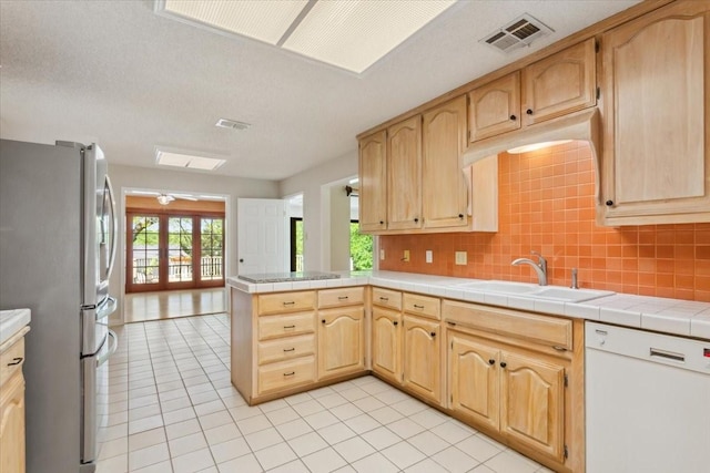 10010 Lost Oak Ridge Dr, Woodway, TX 76712 - kitchen featuring dishwasher, freestanding refrigerator, a sink, light tile patterned floors, and plenty of natural light