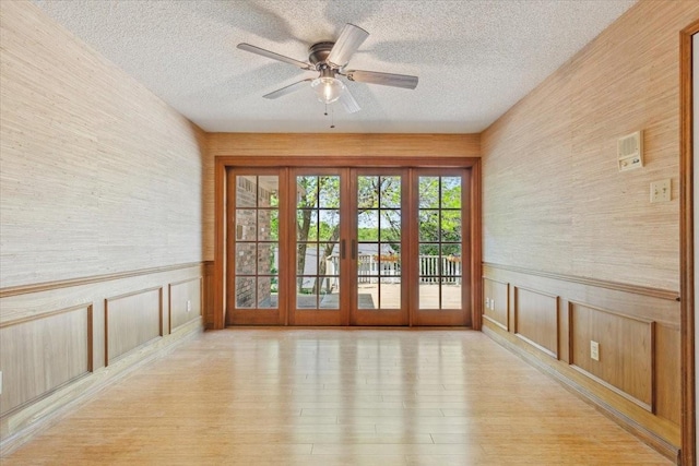 10010 Lost Oak Ridge Dr, Woodway, TX 76712 - doorway to outside with a textured ceiling, light wood finished floors, ceiling fan, and a wainscoted wall
