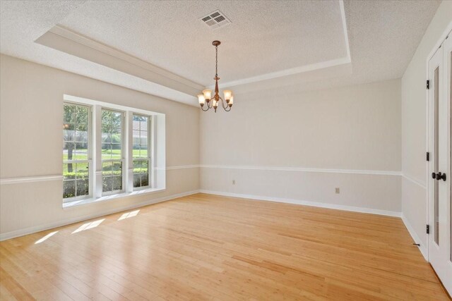 10010 Lost Oak Ridge Dr, Woodway, TX 76712 - spare room featuring a tray ceiling, a chandelier, a textured ceiling, light wood finished floors, and baseboards
