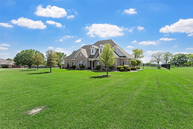 view of front of house with brick siding, fence, and a front lawn