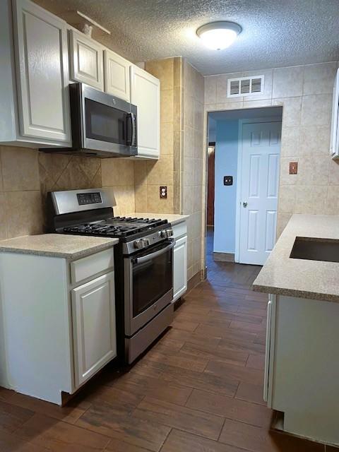 3915 Mather Ct, Dallas, TX 75211 - kitchen featuring appliances with stainless steel finishes, white cabinets, light countertops, a textured ceiling, and a sink